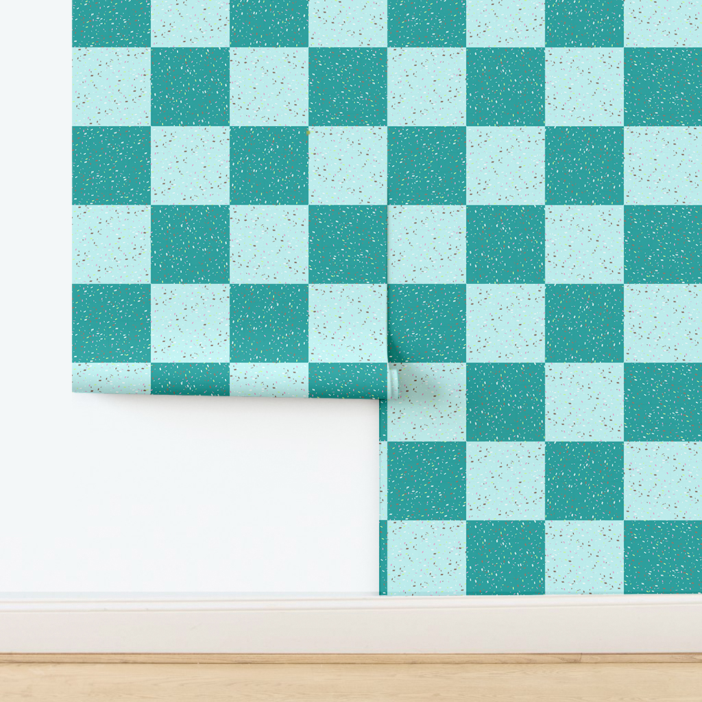 The artwork features a repeating geometric pattern of symmetrical shapes resembling elongated, curved diamonds or petals in various shades of blue and green. Each shape is split vertically with one half filled with a light blue and the other half filled with green or darker blue. The background is a light, almost pastel blue, which provides a soft yet vibrant backdrop. One of the blue shapes near the upper left contains a white starburst element, adding a focal point of brightness to the composition. The overall design conveys a modern, mid-century aesthetic with clean lines and harmonious color contrasts.